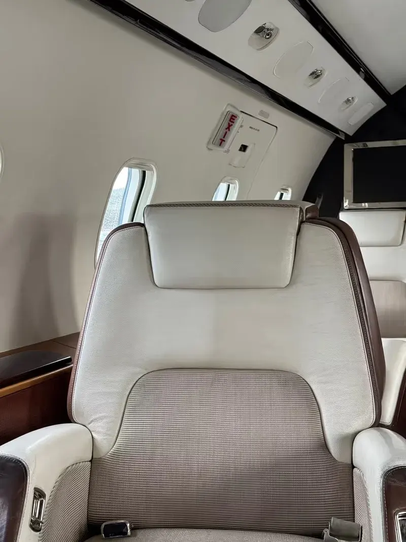 Cream leather aircraft seat detail against wood veneer