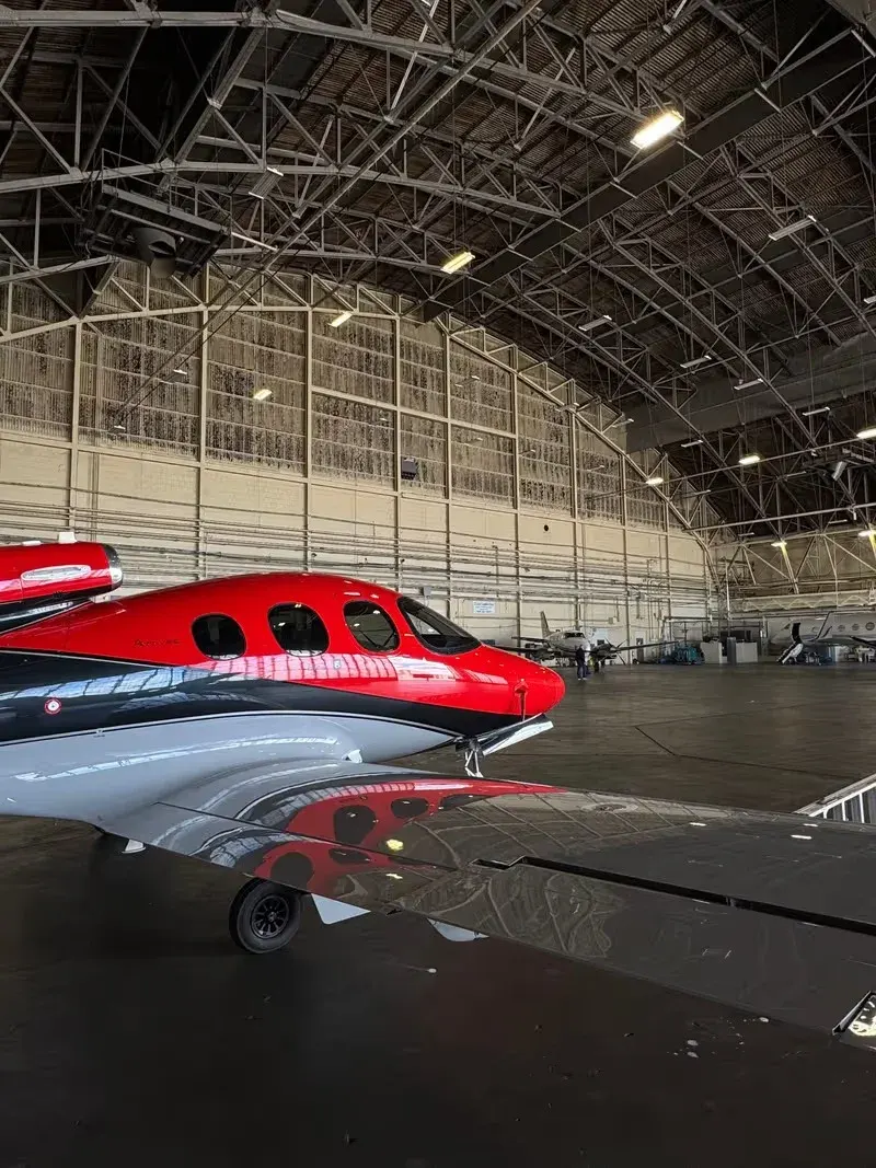 Red and silver helicopter inside a large arched hangar