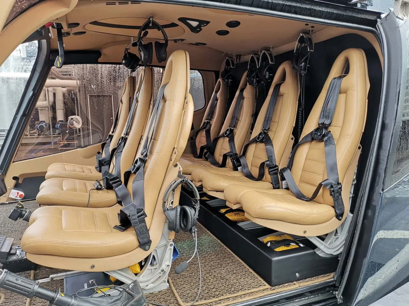 Helicopter cabin with tan leather seating and cleaned safety harnesses