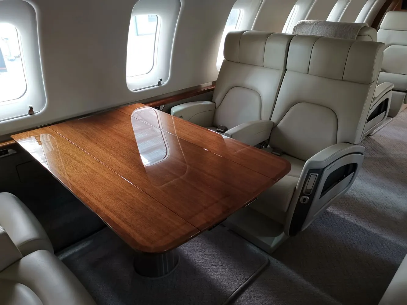 Mirror-finish wood veneer conference table in a light jet cabin