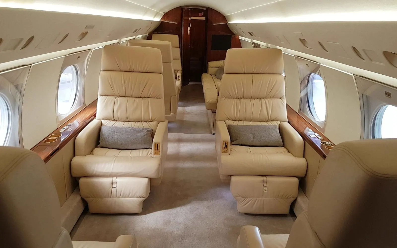 Midsize jet cabin with cream leather seating and wood veneer bulkhead