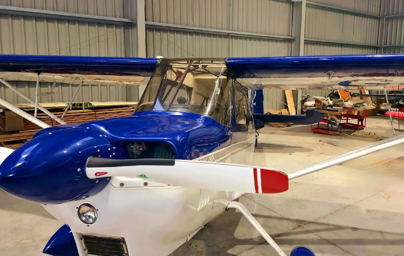 Blue and white light sport aircraft inside a hangar